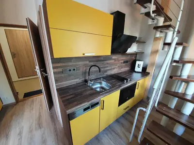 a kitchen with yellow cabinets and a sink at Útulný apartmán na Slapech in Čím