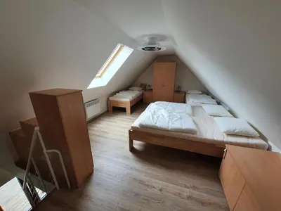 a attic bedroom with two beds and a window at Útulný apartmán na Slapech in Čím