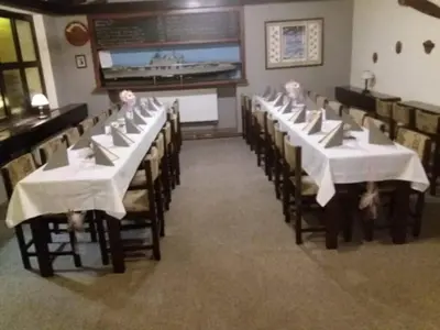 a row of tables in a restaurant with white table settings at Restaurace-Penzion U Pilota in Kněževes