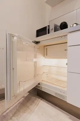 an empty kitchen with white cabinets and a refrigerator at Apartment Mostecka in Prague