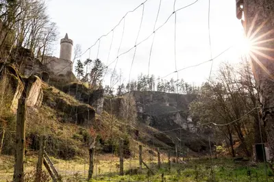 a barbed wire fence in front of a hill with a lighthouse at Roubenka pod hradem Kokořín in Kaninský Dŭl