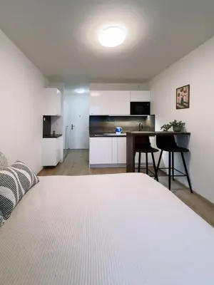 a bedroom with a white bed and a kitchen at Studio apartments Kubanske in Prague