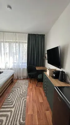 a hotel room with a bed and a desk with a television at VilaVala in Nymburk