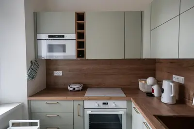 a kitchen with white cabinets and white appliances at Elegant Riverside Apartment with Breathtaking Rock Views in Prague