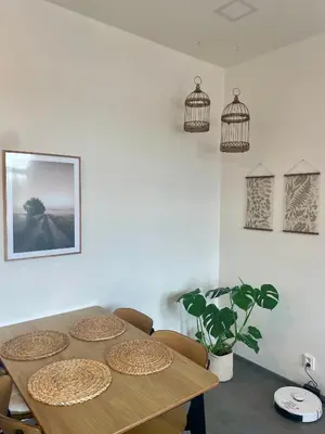 a dining room with a table and chairs and bird cages at Elegant Riverside Apartment with Breathtaking Rock Views in Prague