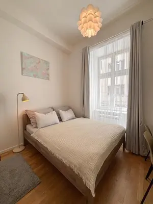 a bedroom with a bed and a large window at Museum Park Apartment in Prague