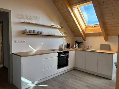 a kitchen with white cabinets and a skylight at Apartmány Hrachov in Svatý Jan