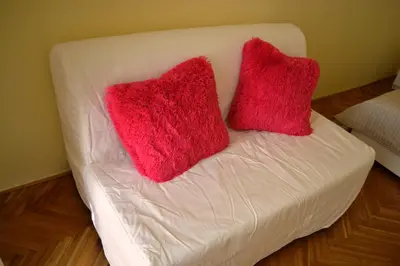 a white couch with two red pillows on it at Sunflower 2BDR Flat By Ruterra in Prague