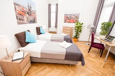 a bedroom with two beds and a desk with a laptop at Florentinum Residence Prague Old Town in Prague