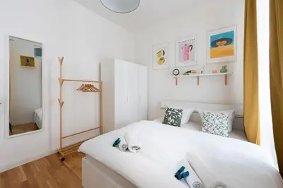 a small bedroom with a white bed and a mirror at Peter's Square Residence in Prague