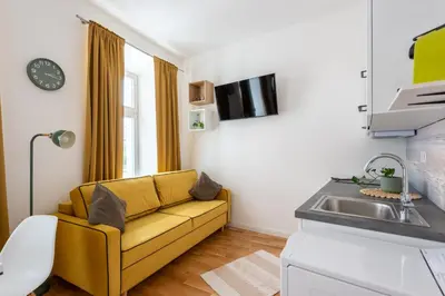 a living room with a yellow couch and a sink at Peter's Square Residence in Prague