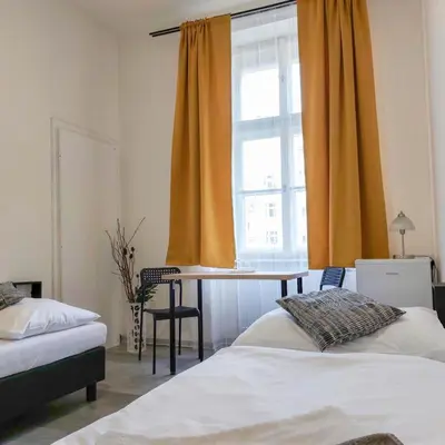a bedroom with two beds and a table and a window at Ubytování blízko národního muzea A1 in Prague