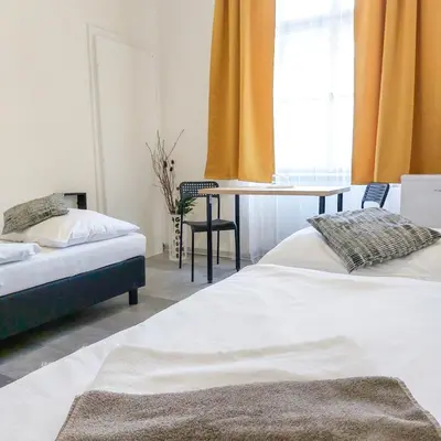 two beds in a room with a table and a window at Ubytování blízko národního muzea A1 in Prague