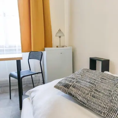 a bedroom with a bed and a chair and a window at Ubytování blízko národního muzea A1 in Prague