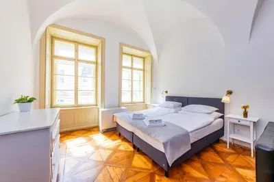 a bedroom with a large bed and two windows at Nerudova Lesser Town Apartments in Prague