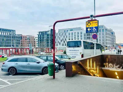 two cars parked in a parking lot with a bus at New building New apartment at Andel Metro Station in Prague