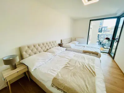 two beds in a bedroom with a large window at New building New apartment at Andel Metro Station in Prague