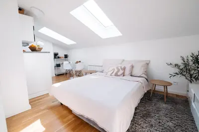 a white bedroom with a bed and a table at Modern Flat in Iconic Location in Prague