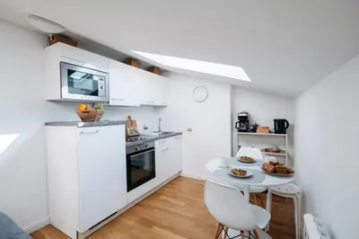a kitchen with white cabinets and a table with food on it at Modern Flat in Iconic Location in Prague