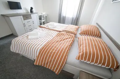 a bedroom with two beds with orange and white sheets at Penzion a restaurace U Jágrů in Kladno
