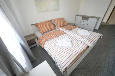 a bedroom with a bed with orange and white sheets at Penzion a restaurace U Jágrů in Kladno