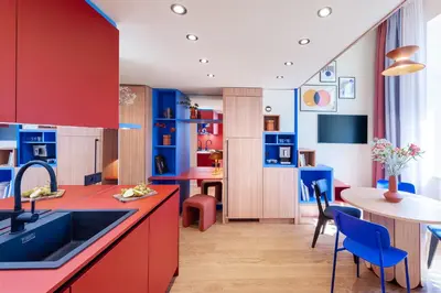 a kitchen with red and blue cabinets and a table at TurnKey I Vinohrady Modern Apartments in Prague