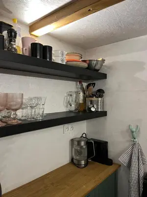a kitchen with black shelves on the wall at Králíkova chatka in Kaliště