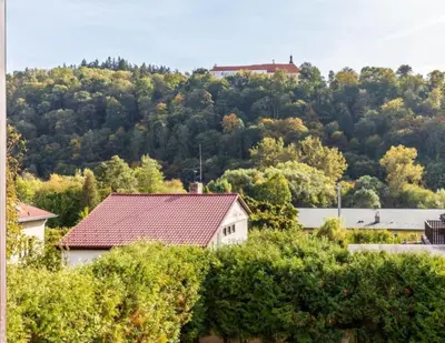 a house with a mountain in the background with trees at Apartment in a family home in Chocerady