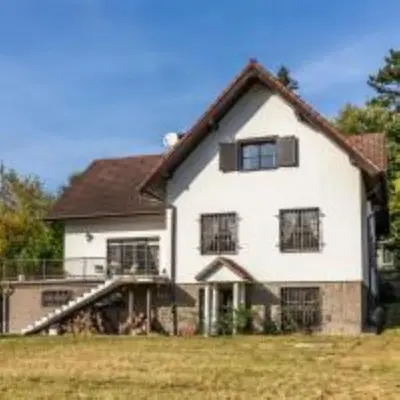 a large white house with black windows in a field at Apartment in a family home in Chocerady