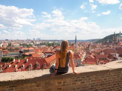 a woman sitting on a wall looking at a city at Nový pokoj u Pražského výstaviště A3 in Prague