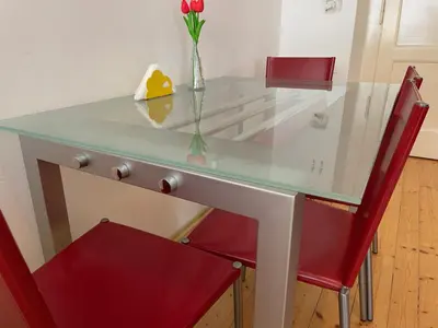 a glass table with a vase of flowers and a red chair at Apartment Flora Lobkovic in Prague