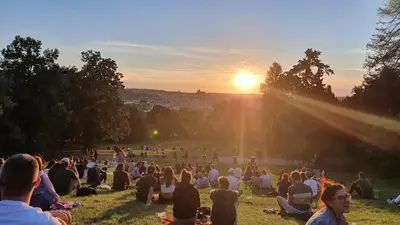 a crowd of people sitting in the grass watching the sunset at Prague Vinohrady Apartment in Prague