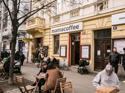 a group of people sitting at a table in front of a store at Prague Vinohrady Apartment in Prague