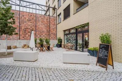 a patio with a umbrella and tables and a building at Blueground Holešovice museums foodie area PRG-11 in Prague