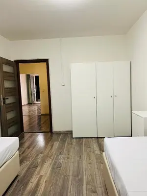 a white bedroom with two beds and a wooden floor at Chodov apartmán in Prague
