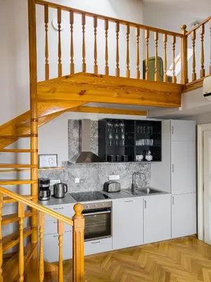 a kitchen with white cabinets and a wooden staircase at Under the Bells of Týn Church in Prague