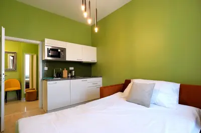 a green room with a bed and a kitchen at Luxemi Apartments I Wenceslas Square in Prague