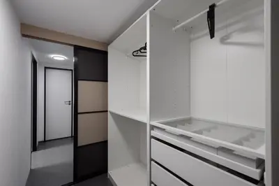a walk in closet with white cabinets and a black door at Family duplex apartment near center in Prague