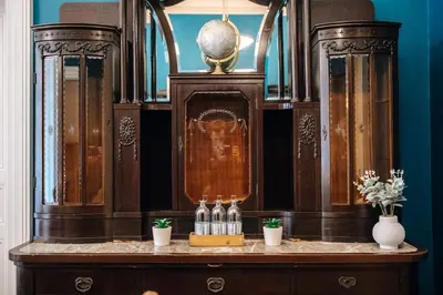 a wooden cabinet with bottles on a table at WagnerStays Grand Nest 6BD Billiard&Sauna&Cinema in Prague
