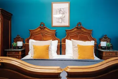 a blue bedroom with two wooden beds with yellow pillows at WagnerStays Grand Nest 6BD Billiard&Sauna&Cinema in Prague