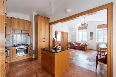 a kitchen with wooden cabinets and a living room at Stay Beneath Prague Castle Where Mozart Performed in Prague