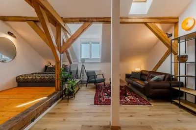 a living room with exposed beams and leather furniture at Parkview Studio in Prague
