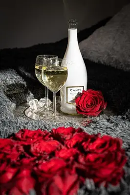 two glasses of wine next to a bottle and roses at Victory Castle Suite in Prague