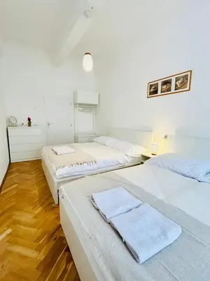 three beds in a room with white walls and wooden floors at New apartment near Wenceslas Square in Prague