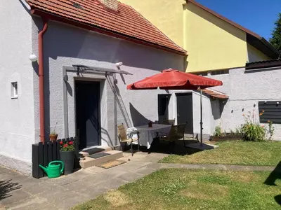 a patio with a red umbrella and a table with a bench at Domek Jiráskova in Dobříš