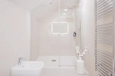 a white bathroom with a sink and a shower at Prague Days - Two-Bedroom Maisonette with AC and Terrace with Grill in Vinohrady in Prague