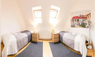 two beds in a room with two windows at Kozi Loft Residence Prague Old Town in Prague