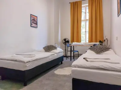 two beds in a room with a table and a window at Soukromý pokoj B4 káva v ceně in Prague