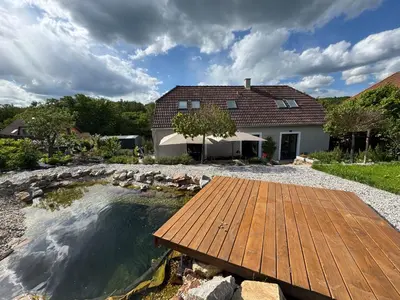 a backyard with a pond and a wooden deck at Private house with garden in Nový Jáchymov