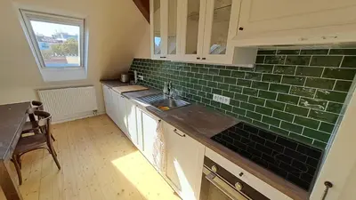 a kitchen with a sink and green tile on the wall at Prague Urban Oasis Loft in Prague